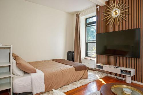 a bedroom with a bed and a flat screen tv at Private Double Queen Suite in Brooklyn Brownstone in Brooklyn