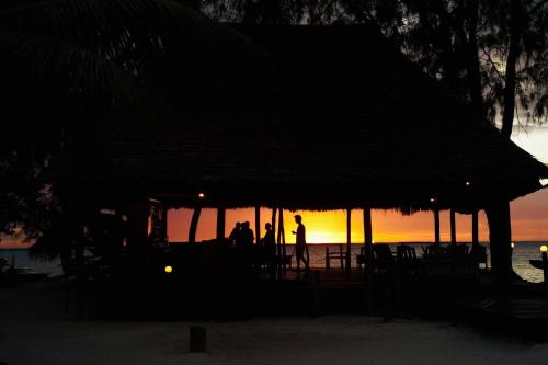 a group of people standing under a hut on the beach at Outdoor Cinema Group Friendly Retreat in Pingwe