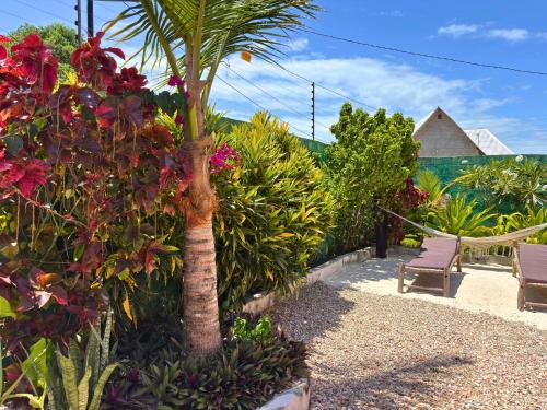 a palm tree in a garden with flowers at Outdoor Cinema Group Friendly Retreat in Pingwe