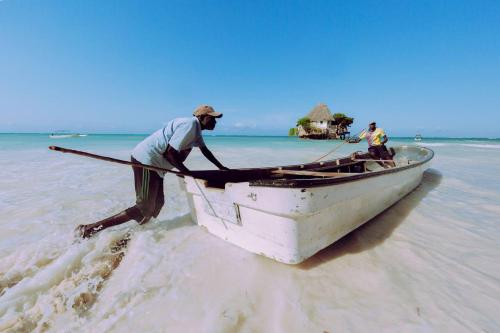 two men in a boat on the beach at Outdoor Cinema Group Friendly Retreat in Pingwe