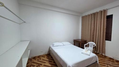 a white room with a bed and a chair at Jorge Chavez Hostel in Lima