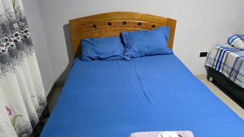 a bedroom with a blue bed with a wooden headboard at Jorge Chavez Hostel in Lima