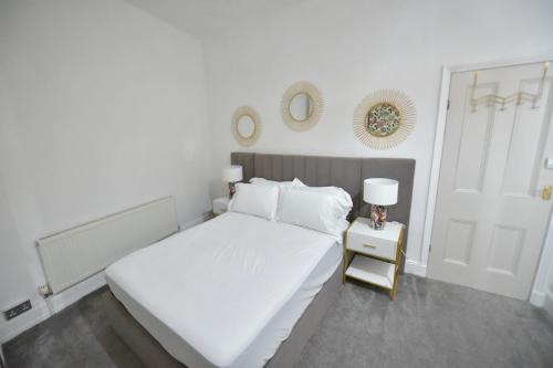 a white bedroom with a bed and a table with a lamp at Spacious & Cosy Double Bed Room Stockport in Stockport