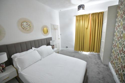 a bedroom with a white bed and a yellow curtain at Spacious & Cosy Double Bed Room Stockport in Stockport