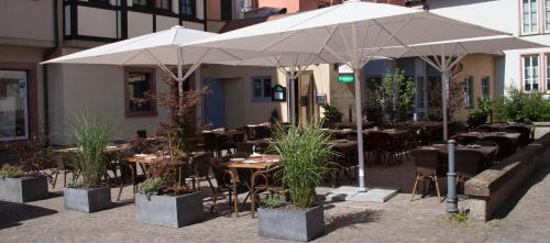 un restaurant avec des tables, des chaises et des parasols dans l'établissement La Flamme Wertheim garni, à Wertheim