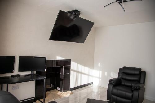 ein Wohnzimmer mit einem Stuhl und einem TV in der Unterkunft Villa Emma - Modern Bungalow with EV Point, Free Parking & Workspace in Northampton