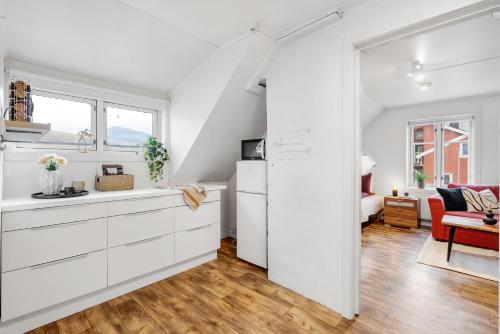 a kitchen with white cabinets and a living room at Studio By The Bridge in Tromsø