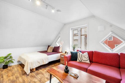 a living room with a red couch and a bed at Studio By The Bridge in Tromsø