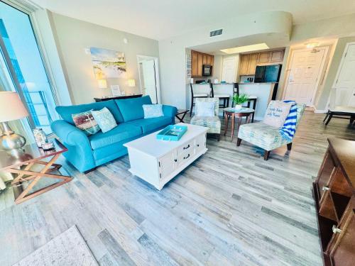 a living room with a blue couch and a table at A Wave From it All in Destin