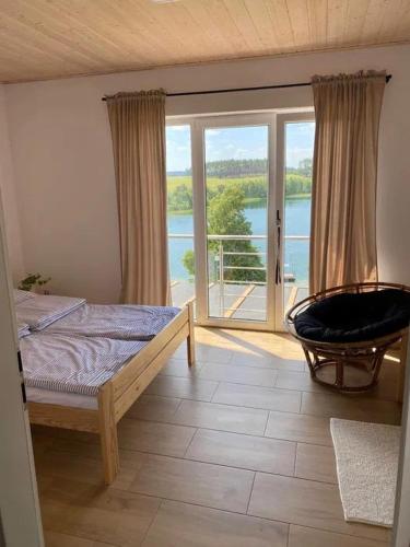 a bedroom with a bed and a balcony with a view at Domek Anastazja na Kaszubach z własną linią brzegową oraz balią in Borzyszkowo