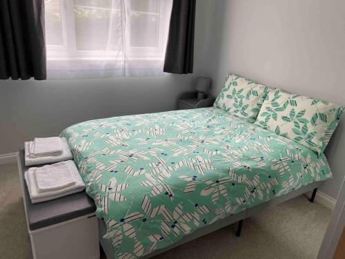 a small bedroom with a bed with a green comforter at Beautiful 1 Bedroom Flat Close to the City Centre in London
