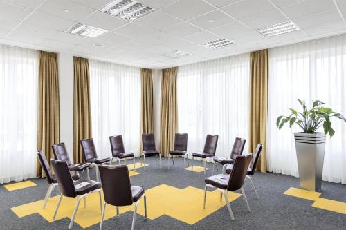 a conference room with chairs and a table and a potted plant at NH Leipzig Messe in Leipzig