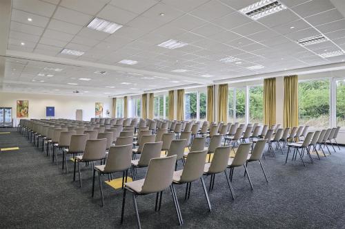 an empty room with rows of chairs and windows at NH Leipzig Messe in Leipzig