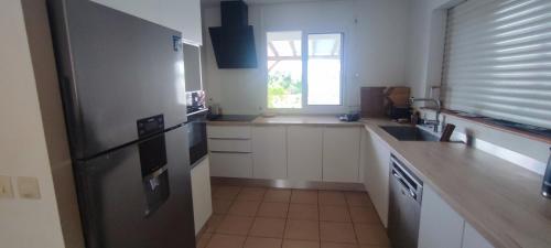 a kitchen with a stainless steel refrigerator and a window at Kaz a Felicia-Villa avec piscine privée et vue mer in Petit-Bourg