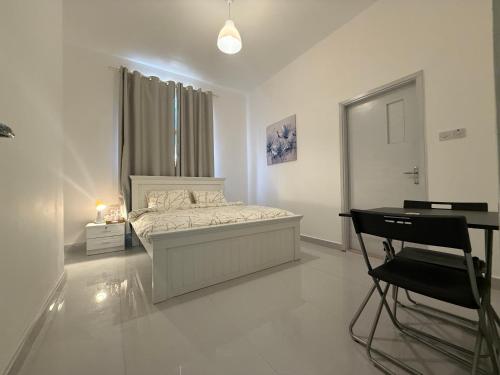 Un dormitorio blanco con una cama y un escritorio. en Flora Residence, en Abu Dabi