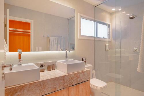 ein Badezimmer mit zwei Waschbecken und einer Glasdusche in der Unterkunft Condomínio Mantra em São Miguel do Gostoso in Reduto