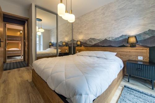 a bedroom with a large white bed and a large mirror at 3 Vallées & cycling Cosy 6 to 8 in the Alps in Orelle