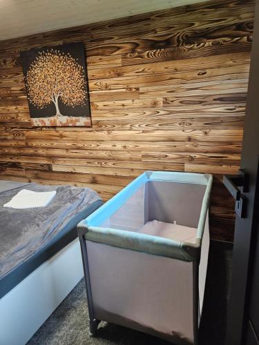 a bedroom with a wooden wall with a bed and a drawer at Chata u lanovky Pustevny in Trojanovice