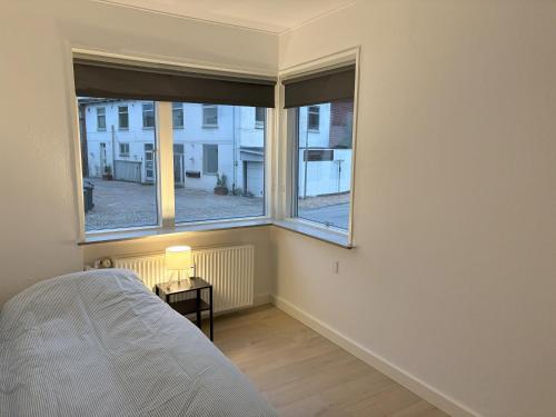 a bedroom with a bed and two large windows at Bright and spacious 3 bedroom with balcony close to the city in Aabenraa