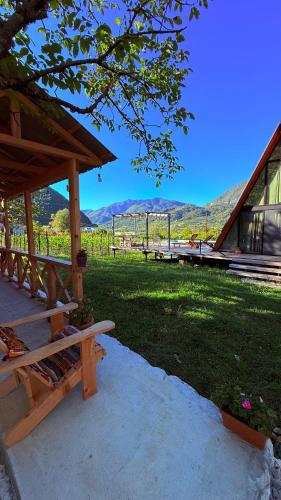a picnic table and benches in a yard with mountains in the background at Rachuli blendi in Ambrolauri