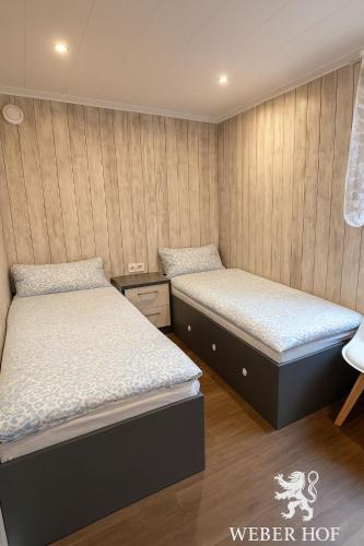 two beds in a room with wooden walls at Weber Hof in Adorf