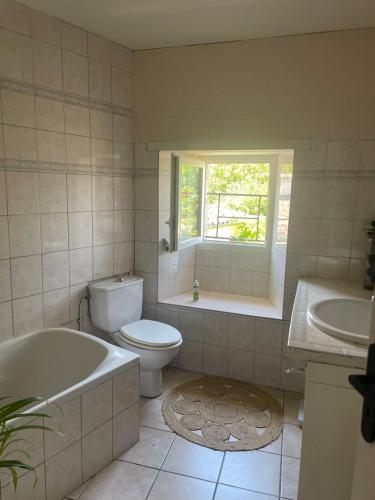 a bathroom with a tub and a toilet and a window at Chambre dans Maison de campagne in Barbaste