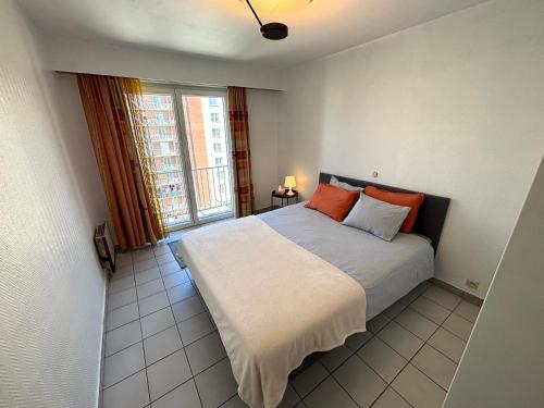 a bedroom with a bed with orange pillows and a window at Villa Elise in Ostend