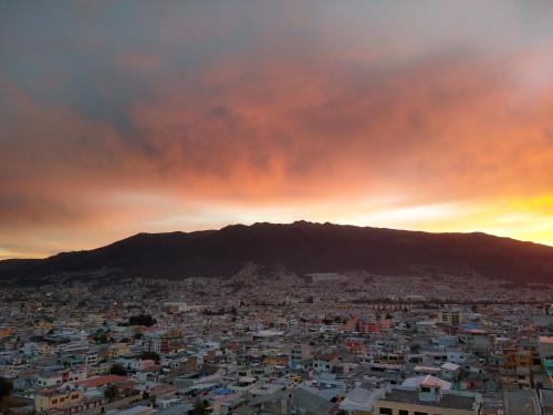 a view of a city at sunset with a mountain at Departamento cerca Solca, Embajada Americana y Estadio Atahualpa con vista al COTOPAXI y la CIUDAD in Quito