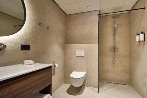 a bathroom with a shower and a toilet and a sink at Eilandhotel Texel - Nieuw geopend hotel in De Cocksdorp