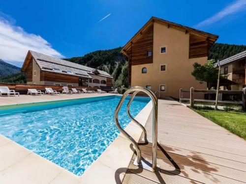 a swimming pool with a chair next to a house at Appartement 3 pieces 6 personnes, 2 chambres, avec piscine l'été et au pied des pistes l'hiver in Arvieux