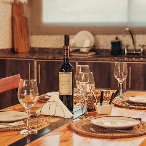 a bottle of wine sitting on a wooden table with glasses at Olivos de Monte in San Miguel del Monte