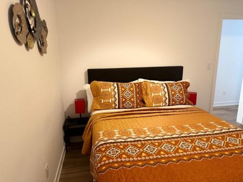 a bedroom with a bed with an orange comforter and pillows at Bright Escape Falls Retreat in Niagara Falls