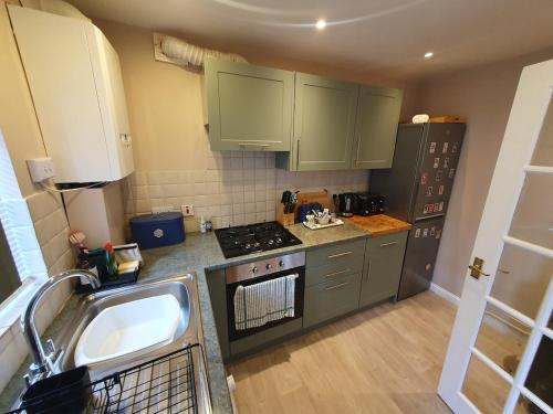 a kitchen with green cabinets and a sink and a stove at Cosy cottage in the centre of Dursley in Dursley