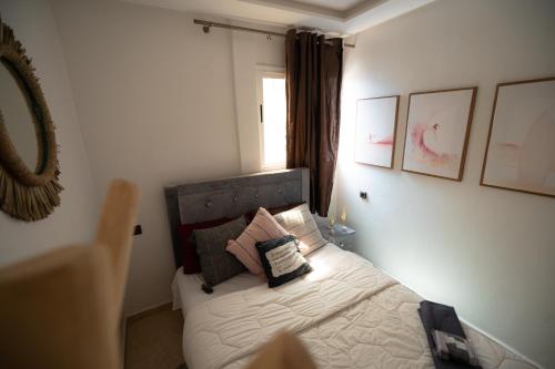 a bedroom with a bed with pillows and a window at Ocean Charm in Tamraght Ouzdar