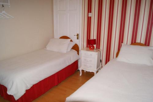two beds in a room with red and white stripes at Apartment in the Heart of Kerry in Knockeen Cross Roads