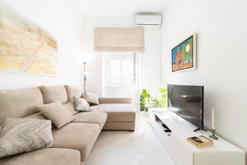 a living room with a couch and a flat screen tv at Peaceful 2-bedroom House with Garden at the heart of Benfica in Lisbon