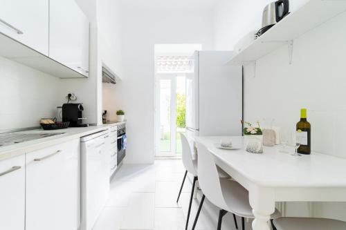 a white kitchen with a white table and chairs at Peaceful 2-bedroom House with Garden at the heart of Benfica in Lisbon