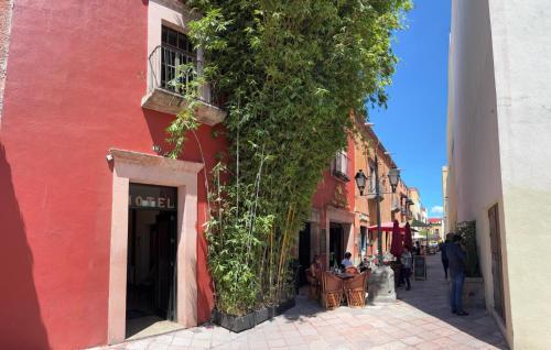a red building with people sitting in chairs on a street at Hotel San Rafael in Querétaro