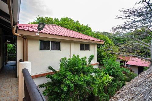 a small house with a red roof and some bushes at Mariposa Belize Beach Resort in Placencia Village
