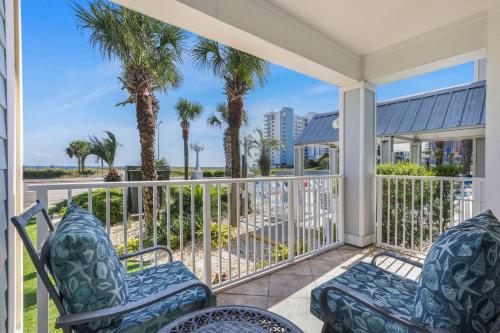a porch with two chairs and palm trees at Grand Caribbean 111 Beach View Condo pool views in Orange Beach