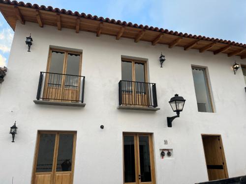 a white building with windows and a balcony at Villas La Cumbre Tapalpa in Tapalpa
