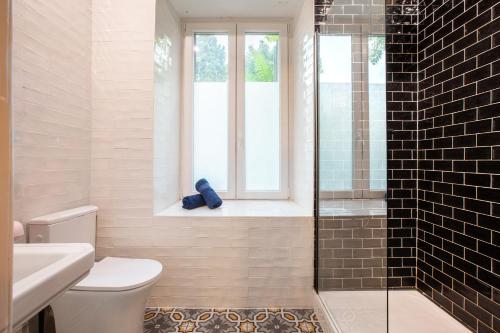 a bathroom with a toilet and a window and a shower at Zenora Loft Hot Tub & Arcade in Downtown in Mulhouse