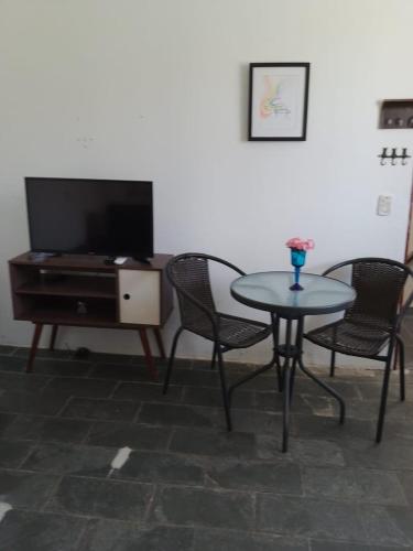 a living room with a table and chairs and a tv at Pousada Bertioga in Bertioga