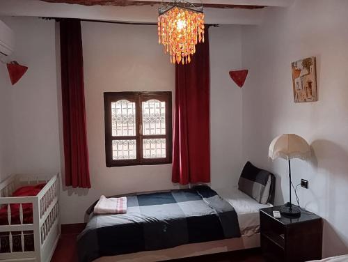 a bedroom with a bed and a window and a chandelier at Tizi Maison d'Hôtes in Telouet