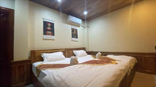 a bedroom with two beds with white sheets at RainForest Guest Lodge in Luang Prabang