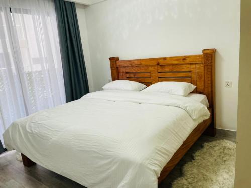 un lit avec des draps blancs et des oreillers dans une chambre dans l'établissement Newrise Gardens Apartments, à Nairobi