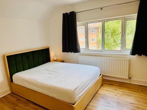Harrow on the Hillにある135 Watford road 3 bedroom villaのベッドと2つの窓がある寝室
