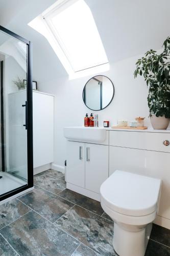 a bathroom with a white toilet and a mirror at The Coachhouse by Solace Stays in Bassaleg