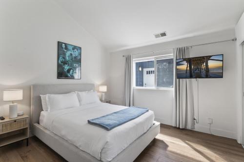 una camera da letto bianca con un letto e una finestra di Steps to Lido Village and the Marina Heart of Lido Island 2 Car Garage a Newport Beach