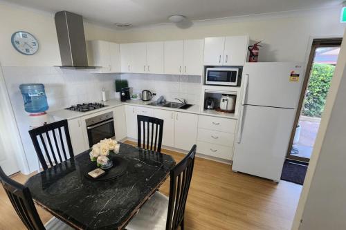 una cucina con tavolo, sedie e frigorifero di Cosy Bayside Studio a Esperance